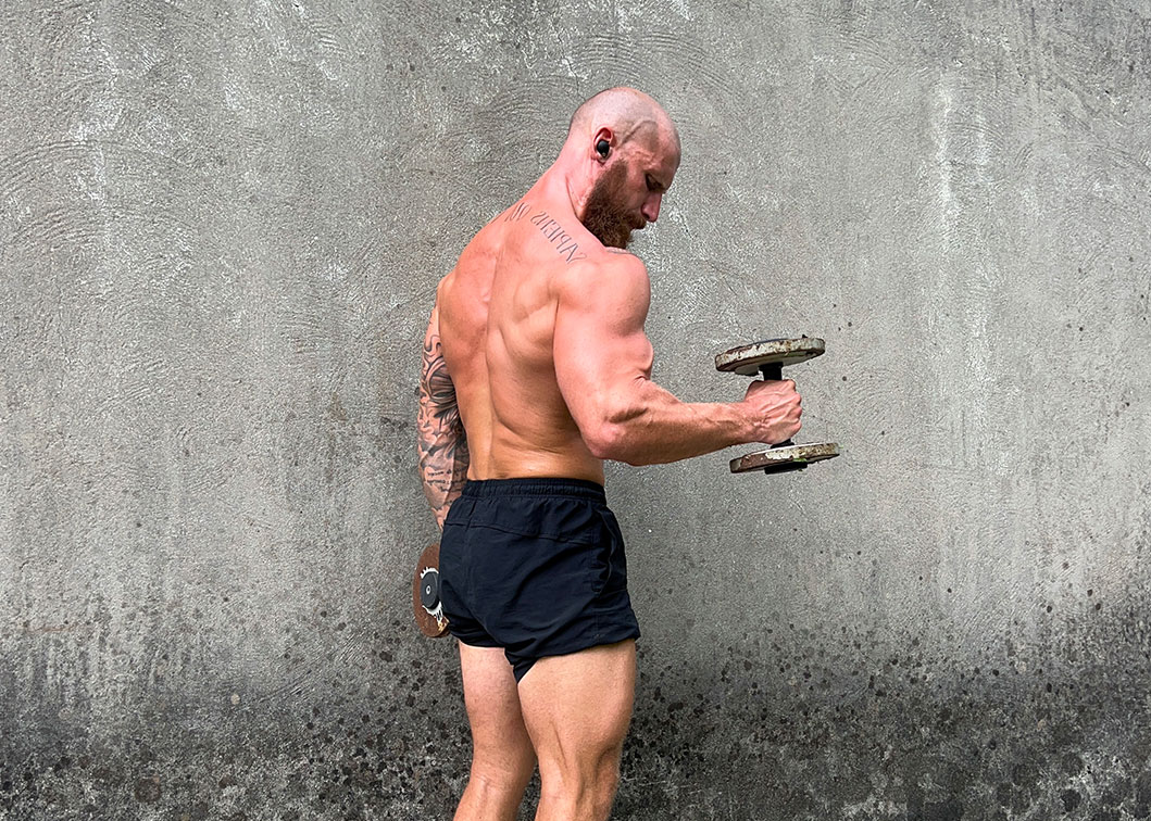 Coach Jordan Fowler lifting a weight facing a concrete wall